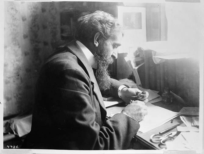 George Wharton James seated at his writing desk, a small bird perched on his finger. Date unknown. Photo courtesy of the Huntington Digital Library.
