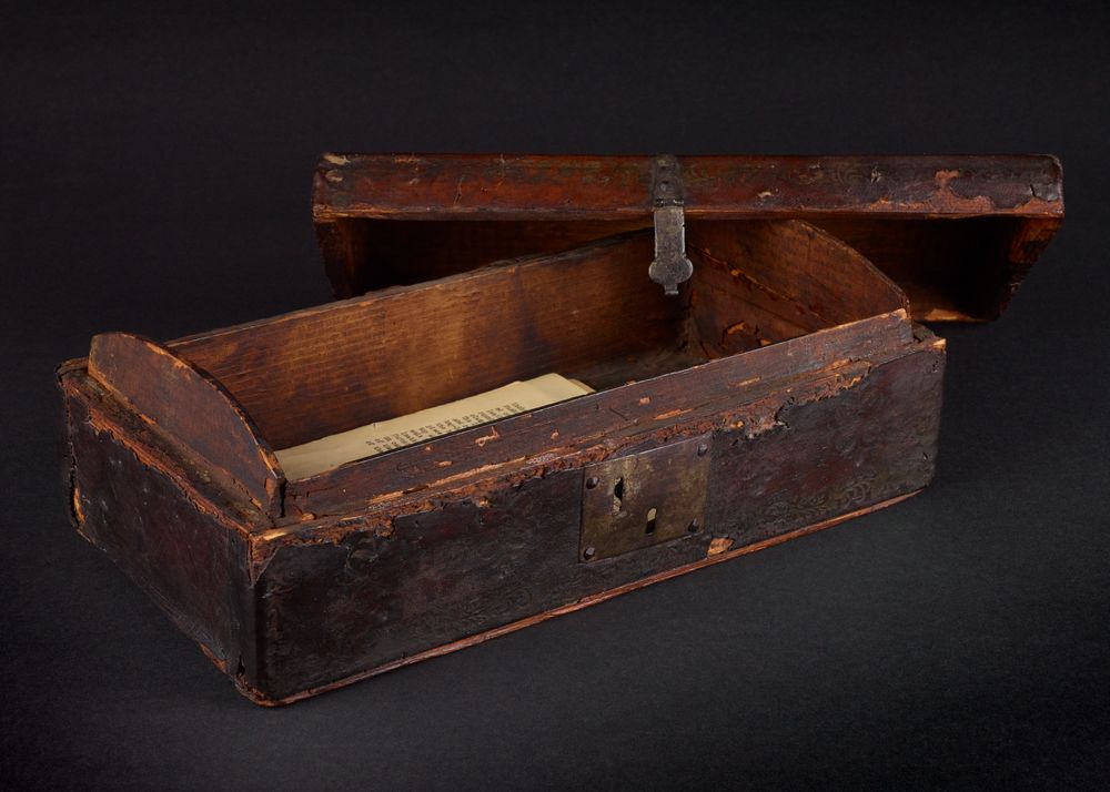 Image of a rectangular wooden 'Dispatch Box, inscribed “GR | Stamp Act Rep’d | March 18, 1766”'. The lid is separate and has a clasp that attaches to the loop on the  box itself.